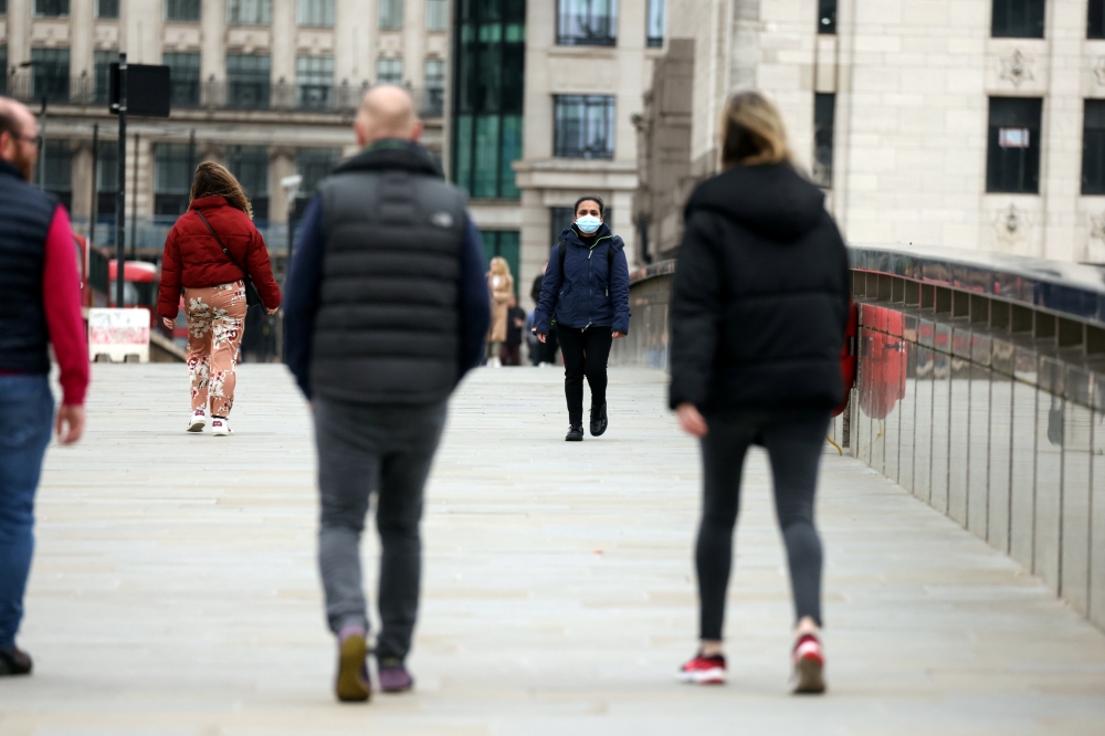 People socially distance while walking across London Bridge as coronavirus disease (COVID-19) lockdown restrictions begin to ease, allowing groups of 6 to meet up outside starting from March 29, in London, Britain, March 28, 2021. REUTERS/Kevin Coombs/Fil