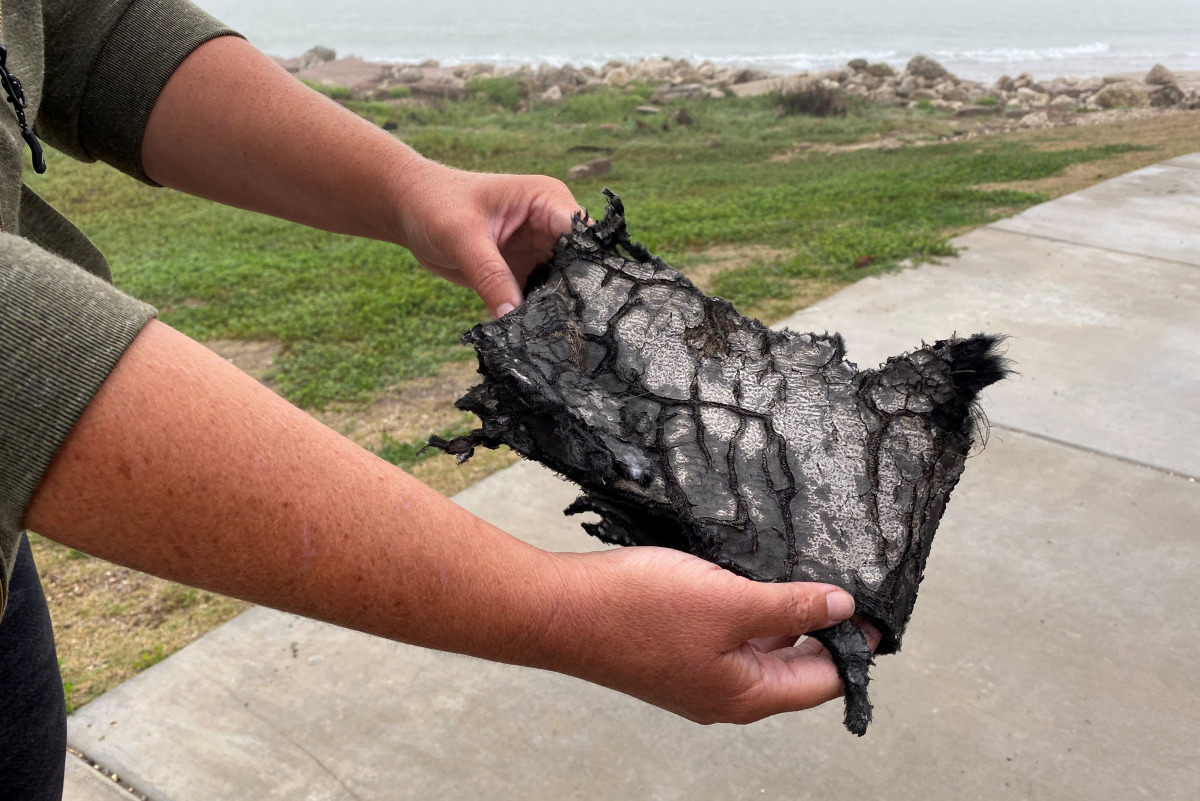 A spectator holds a piece of debris which was blown 5 miles (8 km) from the site where SpaceX test rocket SN11 exploded upon landing, in Boca Chica, Texas, U.S. March 30, 2021. REUTERS/Gene Blevins
