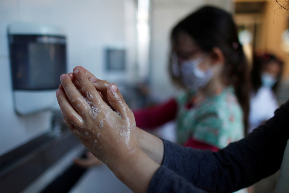 Schoolchildren clean their hands at the private primary school Jeanne D'Arc in Saint-Maur-des-Fosses, near Paris, amid the coronavirus disease (COVID-19) outbreak in France, March 30, 2021. Reuters/Gonzalo Fuentes