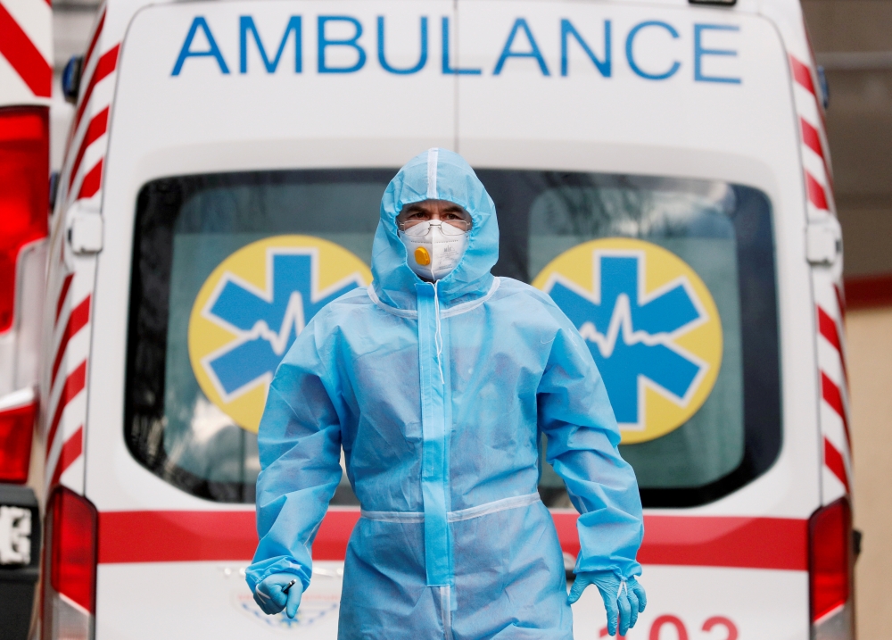 A medical worker wearing protective gear stands next to an ambulance outside a hospital for patients infected with COVID-19 in Kyiv, Ukraine, November 24, 2020. REUTERS/Gleb Garanich/File Photo