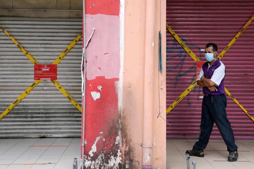 A man wearing a protective mask walks past closed shops, amid the coronavirus disease (COVID-19) outbreak in Kuala Lumpur, Malaysia May 28, 2020. REUTERS/ Lim Huey Teng/File Photo