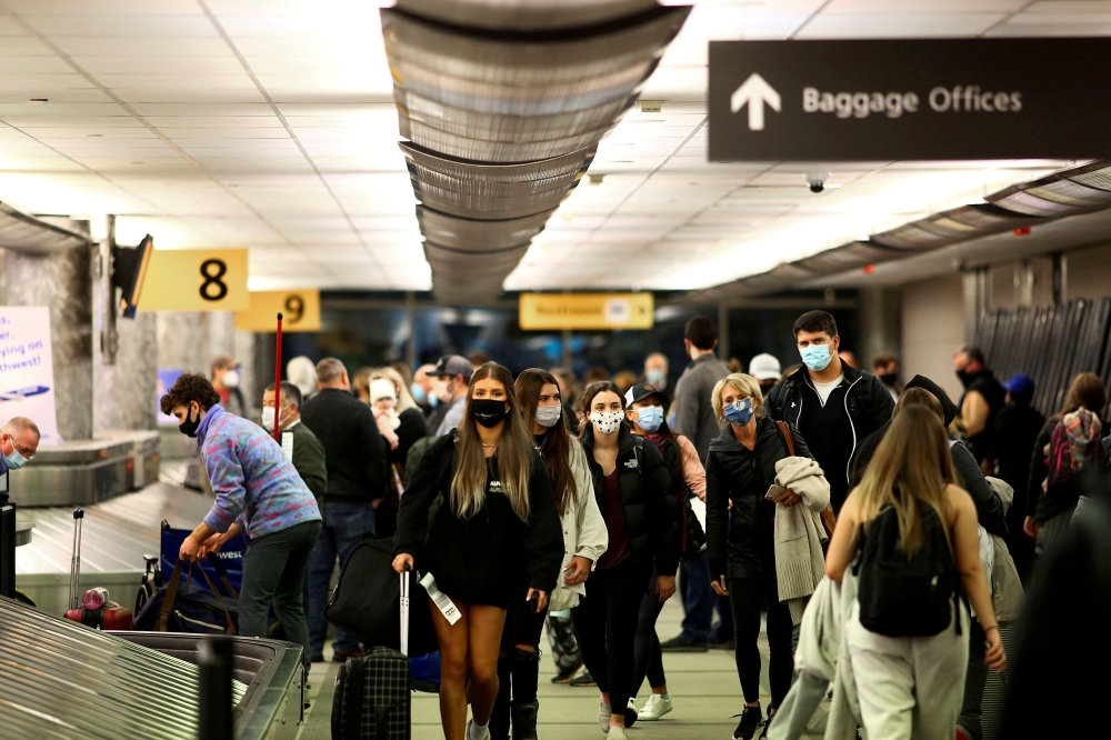 FILE PHOTO: Travelers wearing protective face masks to prevent the spread of the coronavirus disease (COVID-19) reclaim their luggage at the airport in Denver, Colorado, U.S., November 24, 2020. REUTERS/Kevin Mohatt/File Photo