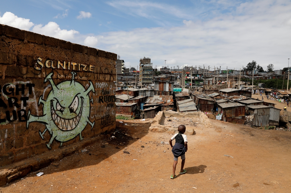 FILE PHOTO: A boy walks in front of a graffiti promoting the fight against the coronavirus disease (COVID-19) in the Mathare slums of Nairobi, Kenya, May 22, 2020. REUTERS/Baz Ratner/File Photo