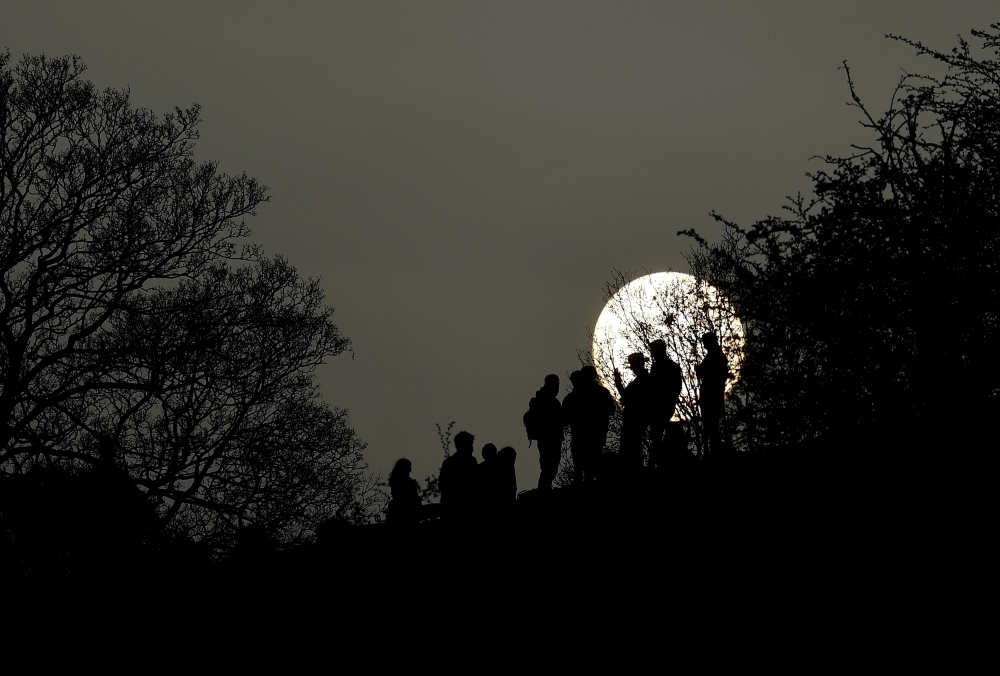 FILE PHOTO: People socialise in Primrose Hill park with the sun seen behind, as lockdown restrictions are eased in England, amid the spread of the coronavirus disease (COVID-19), in London, Britain, April 1, 2021. REUTERS/Toby Melville