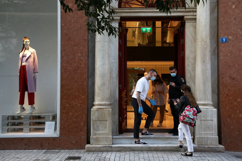 People wearing masks wait to enter a shop on the first day of the re-opening of retail stores, amid the coronavirus disease (COVID-19) pandemic, in Athens, Greece, April 5, 2021. REUTERS/Louiza Vradi