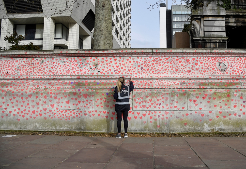 Volunteers and relatives of bereaved paint hearts along a wall beside St Thomas' hospital as a memorial to all those who have died so far in the UK from COVID-19, amid the spread of the coronavirus disease (COVID-19) pandemic in London, Britain, April 1, 