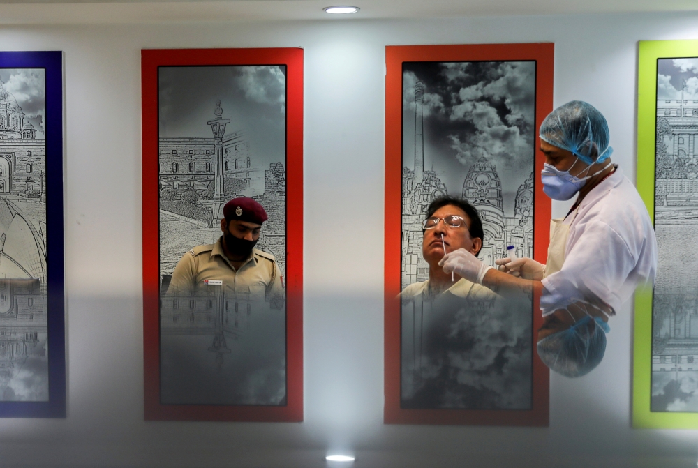 A healthcare worker wearing a protective face mask collects a swab sample from a man, amidst the spread of the coronavirus disease (COVID-19), in New Delhi, India, April 6, 2021. REUTERS/Anushree Fadnavis