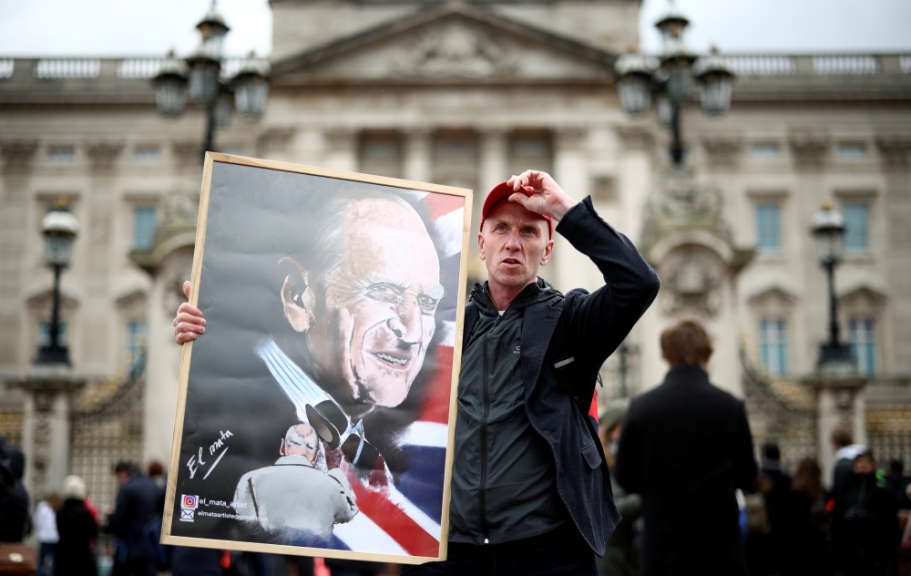 A man hold a poster depicting late Prince Philip outside Buckingham Palace after Britain's Prince Philip, husband of Queen Elizabeth, died at the age of 99, in London, Britain, April 10, 2021. REUTERS/Henry Nicholls