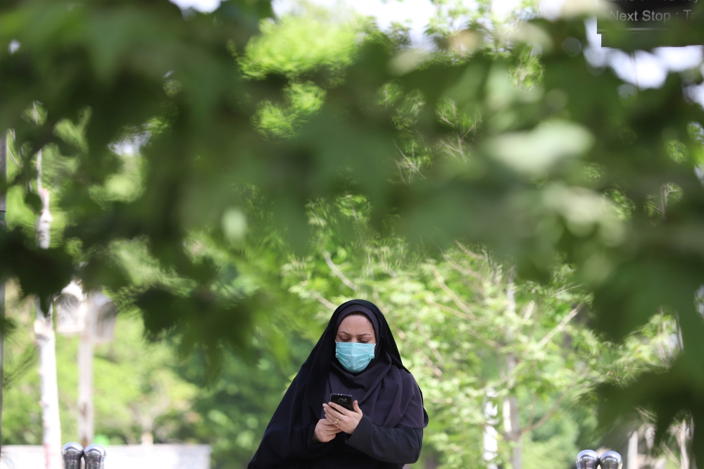 A woman looks at her mobile phone on a street in Tehran, following the tightening of restrictions to curb the surge of COVID-19 cases, Iran April 10, 2021. Majid Asgaripour/WANA