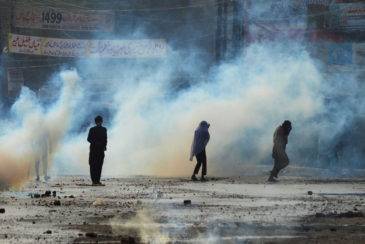 Supporters of the Tehreek-e-Labaik Pakistan (TLP) Islamist political party run to cover amid the smoke of tear gas fired by police during a protest against the arrest of their leader in Lahore, Pakistan April 13, 2021. REUTERS/Stringer
