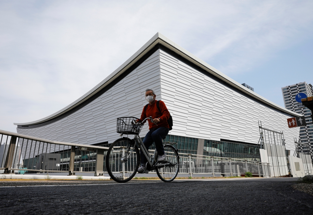 A man wearing a protective mask amid the coronavirus disease (COVID-19) outbreak, cycles past Ariake Arena in Tokyo, Japan, April 8, 2021. Picture taken on April 8, 2021. REUTERS/Kim Kyung-Hoon