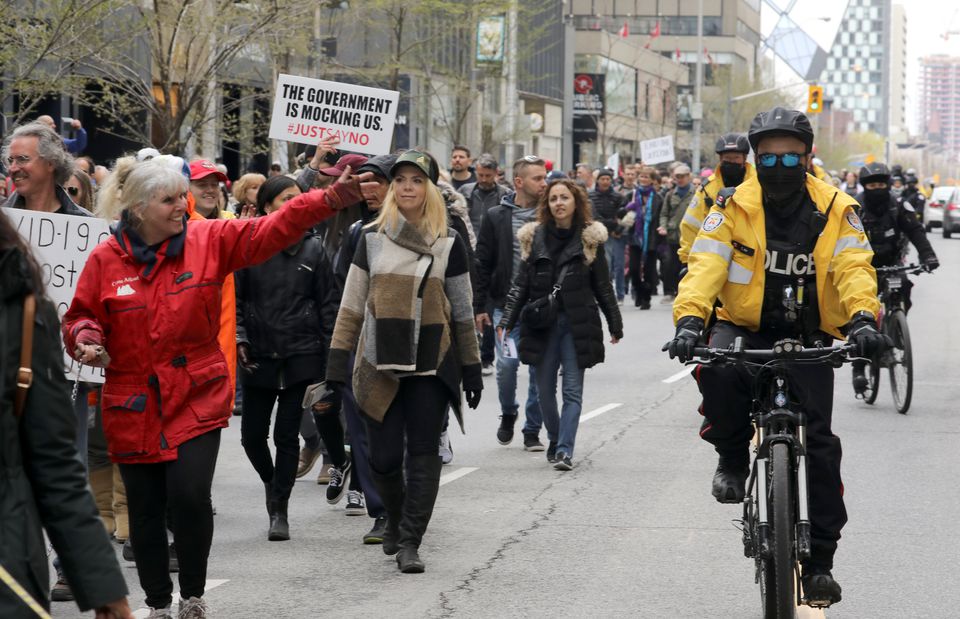 Police offcers ride bikes as demonstrators protest against new coronavirus disease (COVD-19) restrictions, in Toronto, Canada April 17, 2021. REUTERS/Chris Helgren

