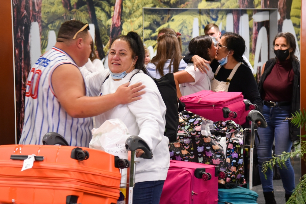 Families and loved ones embrace after arriving on the first Air New Zealand flight to land as quarantine-free travel between Australia and New Zealand begins, in Wellington, New Zealand, April 19, 2021. AAP Image/Ben McKay/via Reuters
