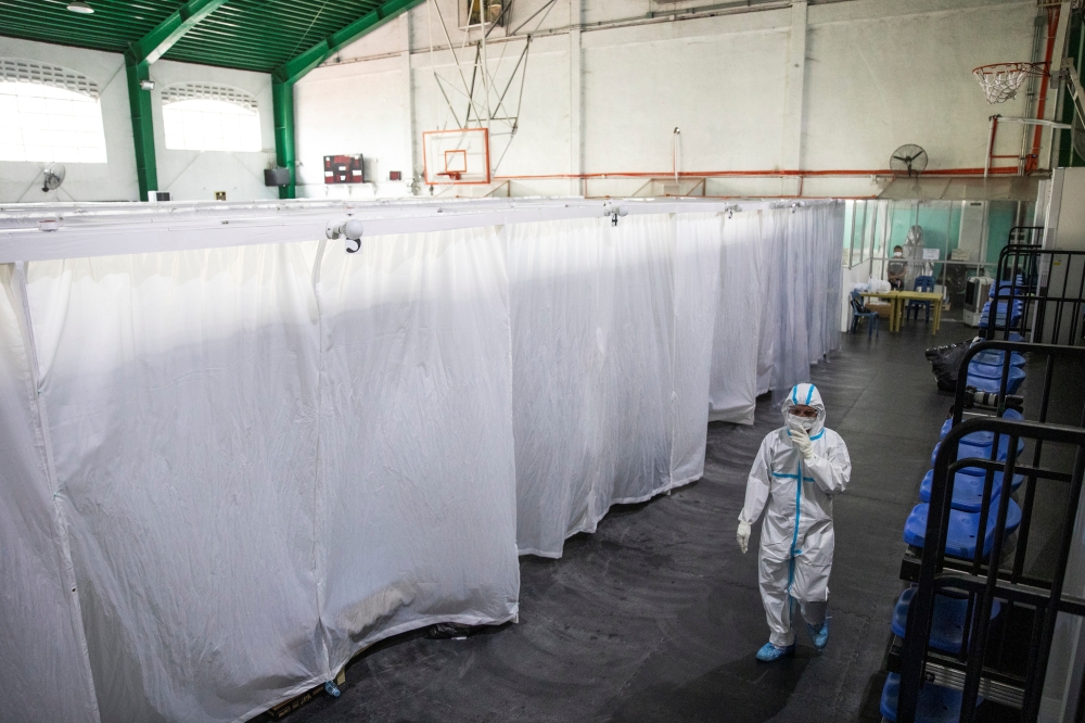 A health worker in personal protective equipment walks inside a covered court used as a quarantine facility for coronavirus disease (COVID-19) patients in Manila, Philippines, April 15, 2021. REUTERS/Eloisa Lopez