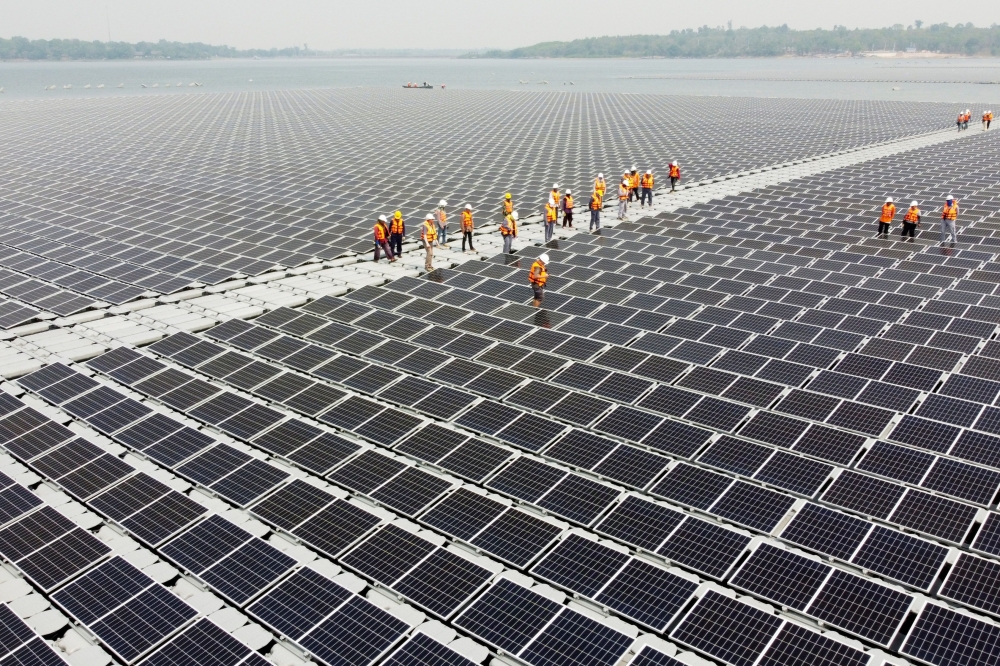 Workers walk between solar cell panels over the water surface of Sirindhorn Dam in Ubon Ratchathani, Thailand April 8, 2021. Picture taken April 8, 2021 with a drone. REUTERS/Prapan Chankaew