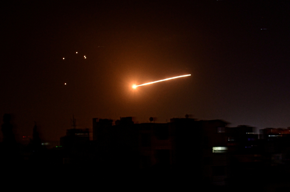 FILE PHOTO: A streak of light is seen in the night sky in the vicinity of the Syrian capital Damascus during what Syrian authorities said was an Israeli air strike, in this handout released by state news agency SANA on February 24, 2020. 