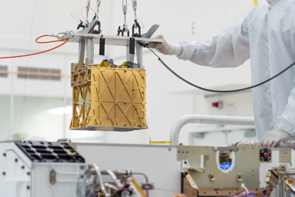 Technicians at NASA's Jet Propulsion Laboratory lower the Mars Oxygen In-Situ Resource Utilization Experiment (MOXIE) instrument into the belly of the Perseverance rover in an undated photograph in Pasadena, California, U.S. NASA/JPL-Caltech/Handout via R