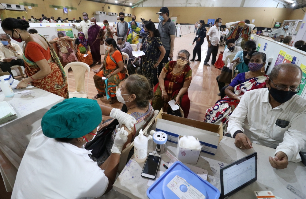 A woman receives a dose of COVISHIELD, a coronavirus disease (COVID-19) vaccine manufactured by Serum Institute of India, as others wait for their turn at a vaccination centre in Mumbai, India, April 26, 2021. REUTERS/Niharika Kulkarni
