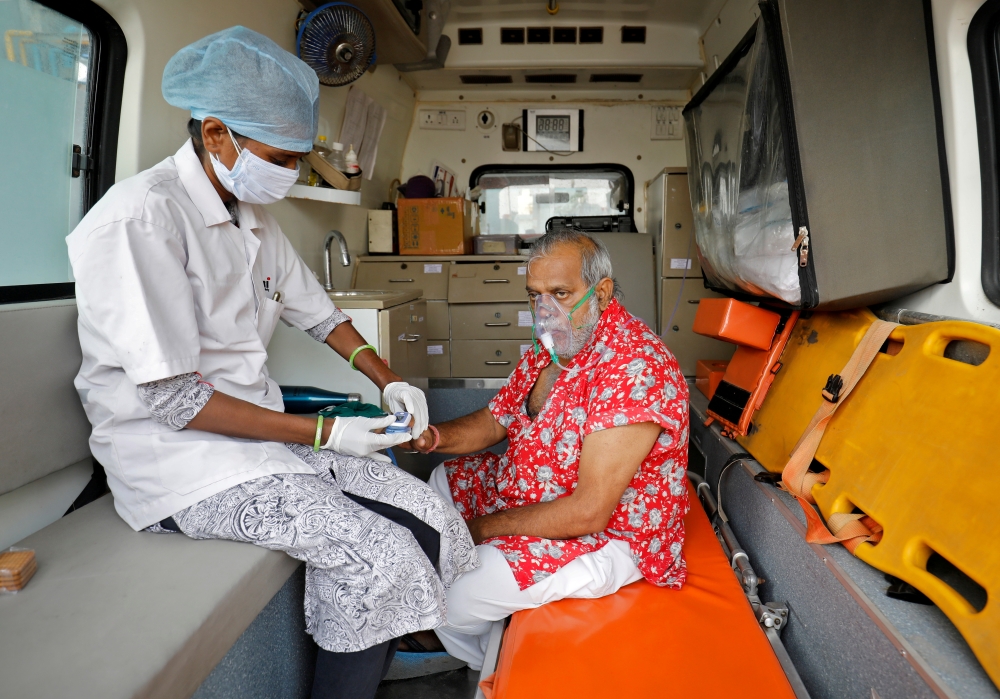 FILE PHOTO: A paramedic uses an oximeter to check the oxygen level of a patient inside an ambulance while waiting to enter a COVID-19 hospital for treatment, amidst the spread of the coronavirus disease (COVID-19) in Ahmedabad, India, April 22, 2021. REUT