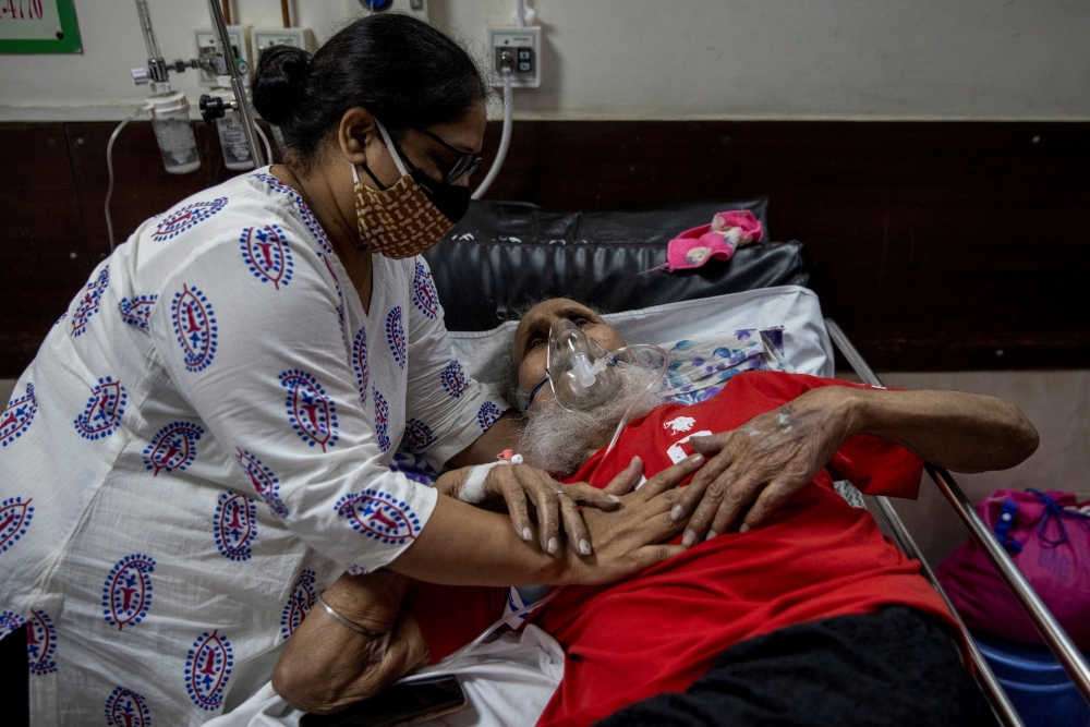 A man suffering from the coronavirus disease (COVID-19) is comforted by his daughter as he receives treatment inside the casualty ward at a hospital in New Delhi, India, May 1, 2021. REUTERS/Danish Siddiqui 