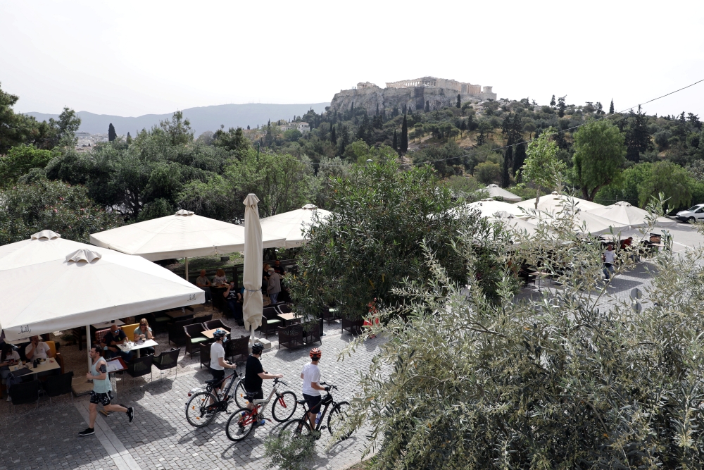 People walk near an outdoor cafe in Thiseio, as restaurants and cafes in Greece open after six months of lockdown, amid the coronavirus disease (COVID-19) outbreak, in Athens, Greece, May 3, 2021. REUTERS/Louiza Vradi