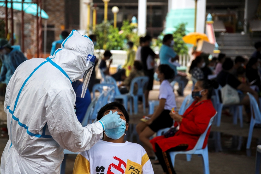 A healthcare worker takes a nasal swab sample from a person for a coronavirus disease (COVID-19) test, at a temple near Klong Toey slum community in Bangkok, Thailand, May 3, 2021. REUTERS/Juarawee Kittisilpa