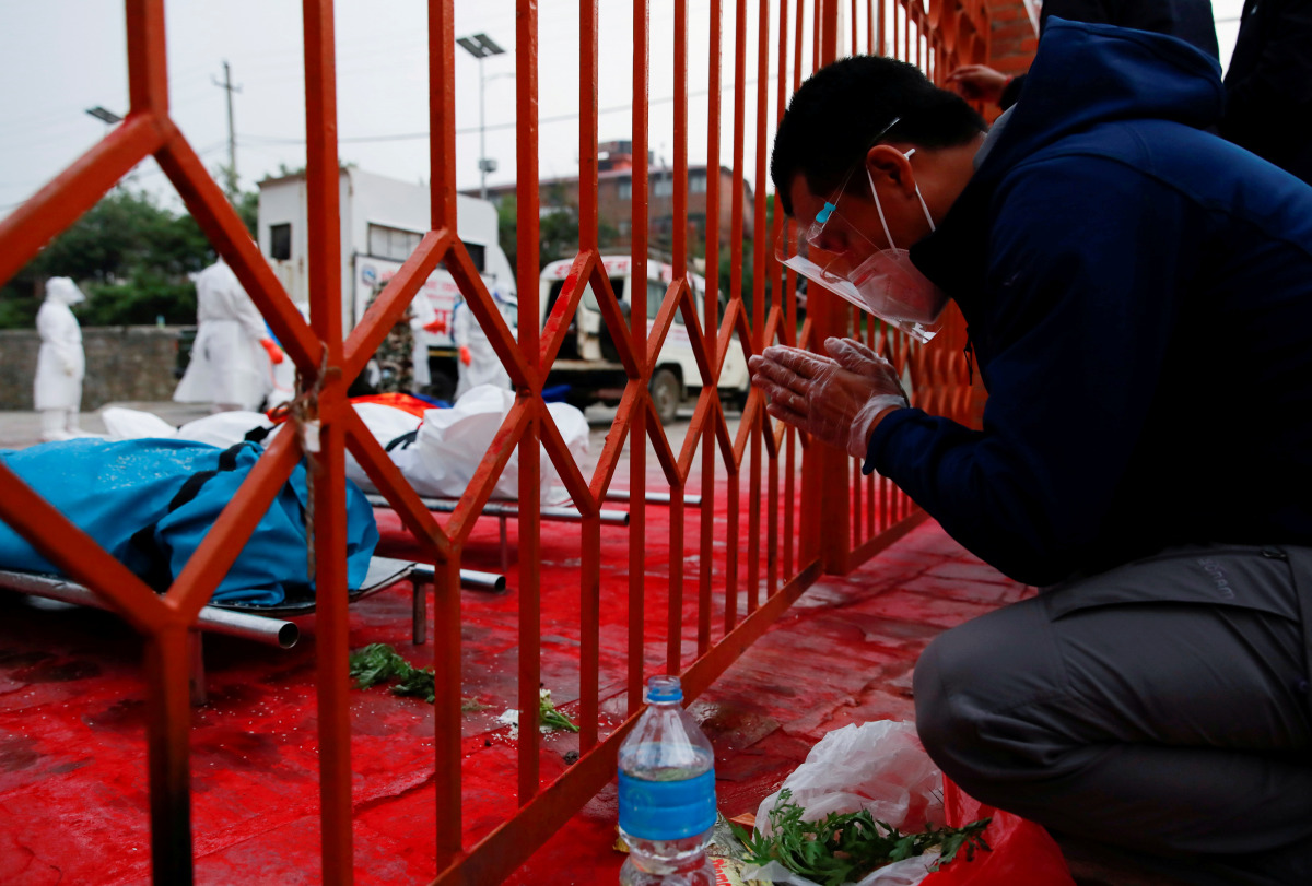 A family member offers a prayer near a coronavirus disease (COVID-19) victim as the country recorded the highest daily increase in deaths since the pandemic began, in Kathmandu, Nepal May 3, 2021. REUTERS/Navesh Chitrakar TPX IMAGES OF THE DAY
