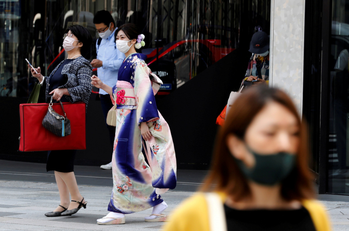 FILE PHOTO: A woman in kimono clad and pedestrians wearing protective face masks, make their way at a shopping district on the first day of the country's third state of emergency, amid the coronavirus disease (COVID-19) outbreak, in Tokyo, Japan, April 25