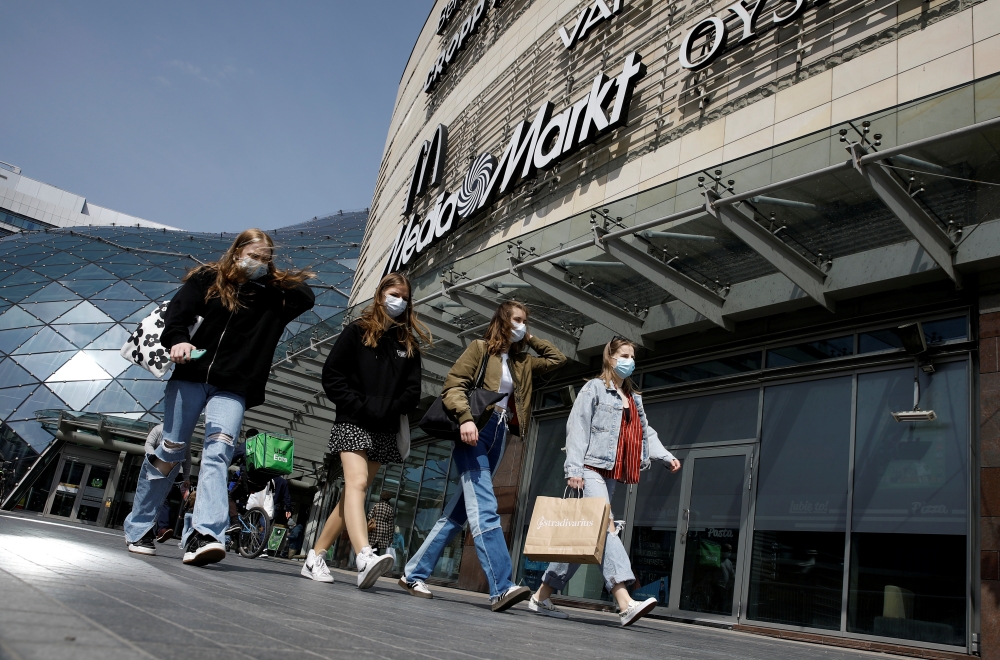 People wearing protecting masks walk in front of the Zlote Tarasy shopping mall in the centre of the city as the government eased coronavirus disease (COVID-19) restrictions, in Warsaw, Poland May 4, 2021. REUTERS/Kacper Pempel/File Photo