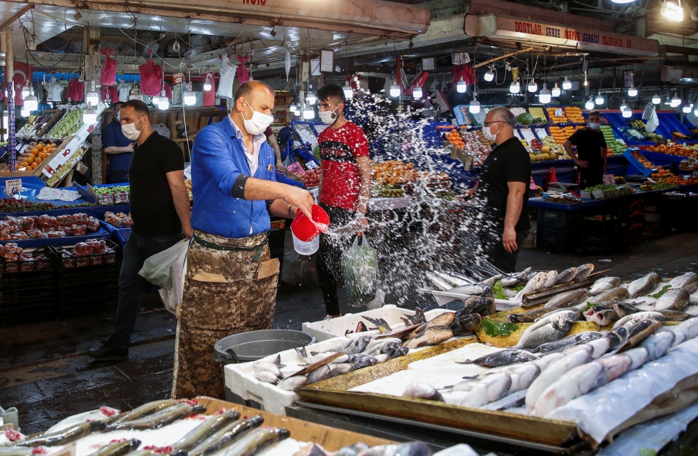 A vendor wears a protective mask at a fish and seafood stall at a local market during a nationwide 