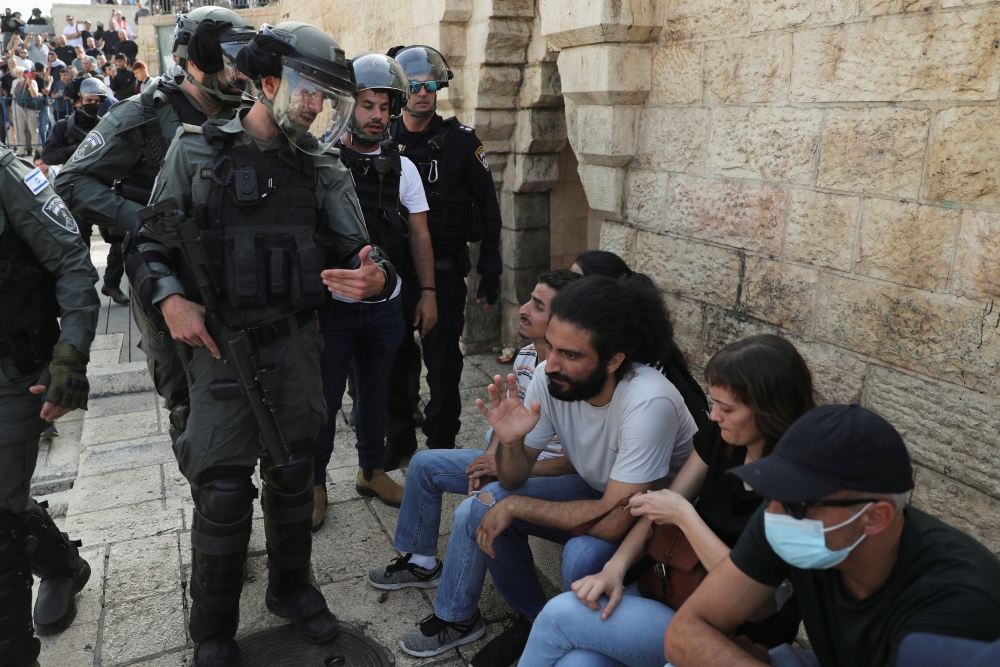 A Palestinian man and an Israeli border policeman gesture amid tension at Damascus Gate just outside Jerusalem's Old City on May 10, 2021. (REUTERS/Ronen Zvulun)