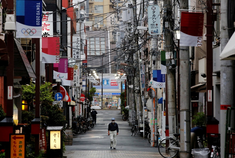 File photo: A man wearing a protective face mask, amid the coronavirus disease (COVID-19) pandemic, walks in a local shopping street decorated with Tokyo 2020 Olympic Games flags, in Tokyo, Japan, May 7, 2021. Reuters/Kim Kyung-Hoon/File Photo