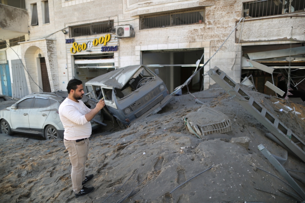 A Palestinian man takes pictures of the damage in the aftermath of Israeli air strikes, amid a flare-up of Israeli-Palestinian violence, in Gaza City May 12, 2021. REUTERS/Suhaib Salem
