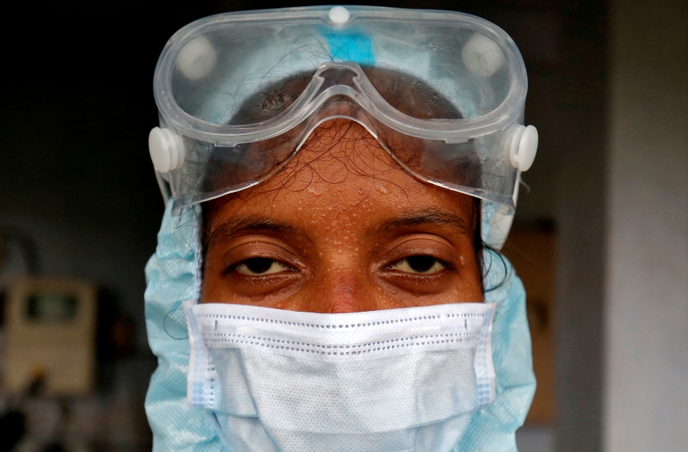 File photo: Beads of sweat run down the forehead of a healthcare worker wearing protective gear after she took swabs from the residents for rapid antigen test, amidst the coronavirus disease (COVID-19) outbreak, at a residential apartment in Ahmedabad, In
