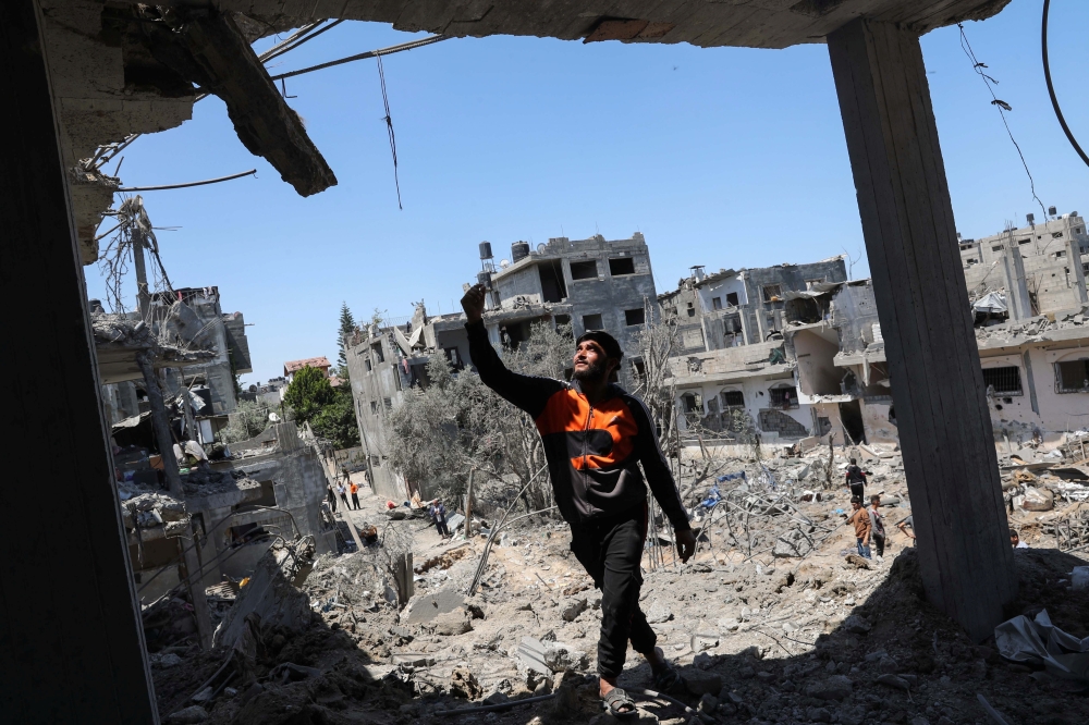 A Palestinian man gestures at the site of destroyed houses in the aftermath of Israeli air and artillery strikes as cross-border violence between the Israeli military and Palestinian militants continues, in the northern Gaza Strip May 14, 2021. REUTERS/Mo