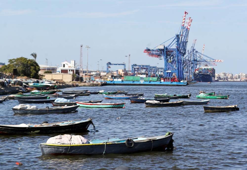 FILE PHOTO: Boats are seen as container ship is beside cranes at the Suez canal near Ismailia port city, northeast of Cairo, Egypt March 5, 2021. REUTERS/Mohamed Abd El Ghany