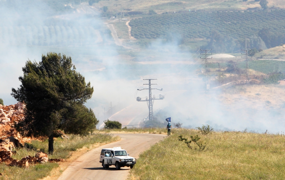 A UN peacekeeper (UNIFIL) stands as smoke rise in the southern Lebanese village of Khiam, near the border with Israel, Lebanon May 14, 2021. REUTERS/Aziz Taher