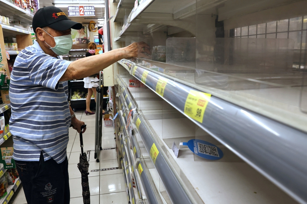 A man takes instant noodles from a near-empty shelf as customers rush to buy their groceries after the government advised people to reduce leaving their homes and limit gatherings due to an increasing number of locally transmitted coronavirus disease (COV