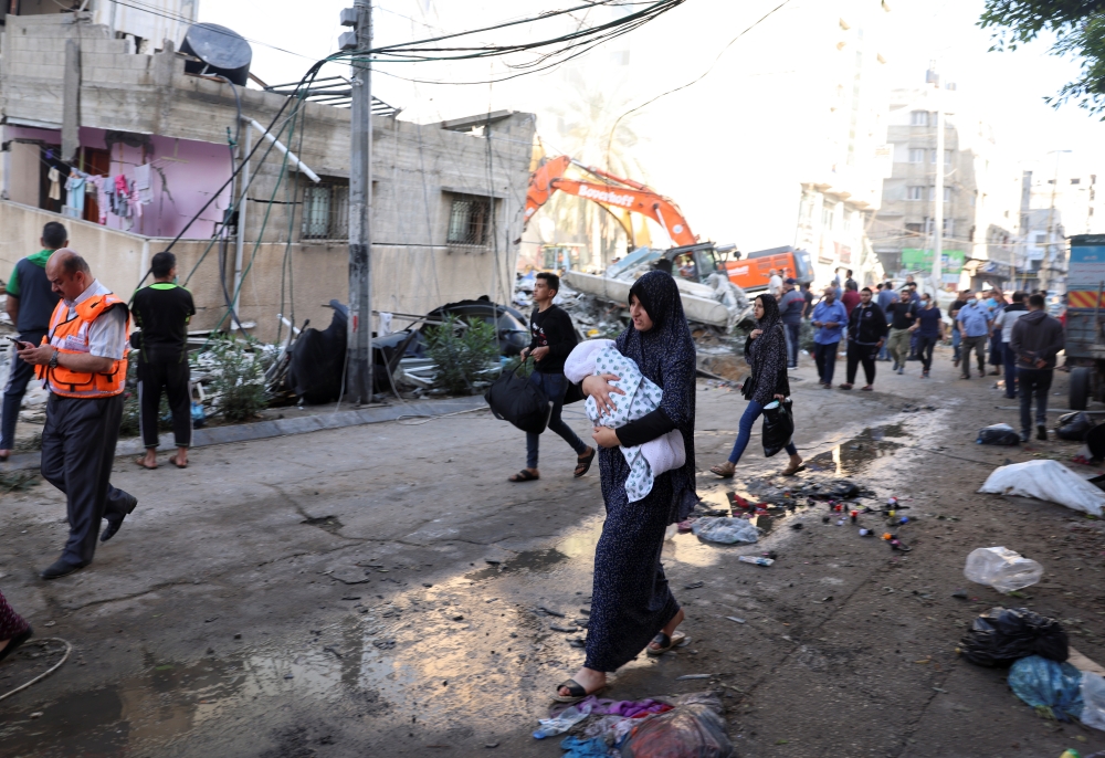 People walk past debris in a street at the site of Israeli air strikes, in Gaza City May 16, 2021. REUTERS/Mohammed Salem
