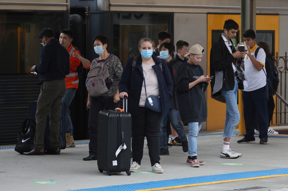 File photo: People, some wearing protective face masks, stand on a train platform at Central Station after new public health regulations were announced for greater Sydney, including compulsory mask-wearing on public transport, following the emergence of n