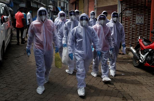 Healthcare workers wearing personal protective equipment (PPE) walk towards different localities before the start of a check-up camp for the coronavirus disease (COVID-19) in Mumbai, India June 27, 2020. REUTERS/Francis Mascarenhas
