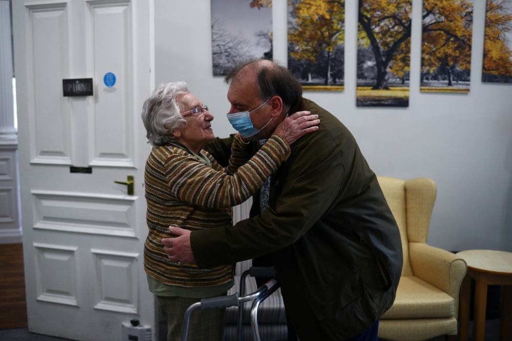 Stephen Crowe hugs is mother Susan Crowe, 96, who is a resident at Alexander House Care Home in Wimbledon, as coronavirus disease (COVID-19) restrictions continue to ease, London, Britain, May 17, 2021. REUTERS/Hannah McKay