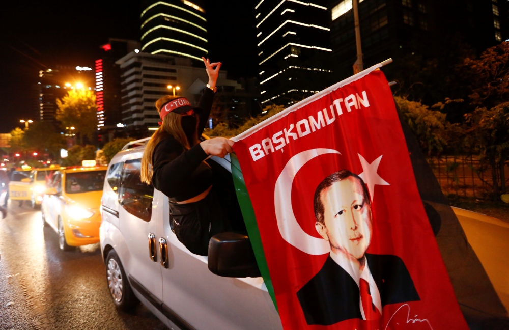 A pro-Palestinian demonstrator holds a flag with an image of Turkish President Tayyip Erdogan as they drive past by the Israeli Consulate in Istanbul, Turkey May 12, 2021. REUTERS/Dilara Senkaya