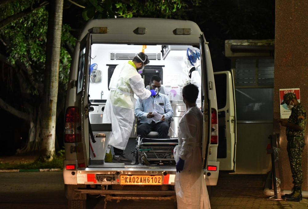 Professional bikers Murthaza Junaid and his brother Muteeb Zoheb, who volunteer as ambulance drivers, tend to a man with breathing difficulty before ferrying him to a hospital for treatment, amidst the spread of the coronavirus disease (COVID-19) in Benga