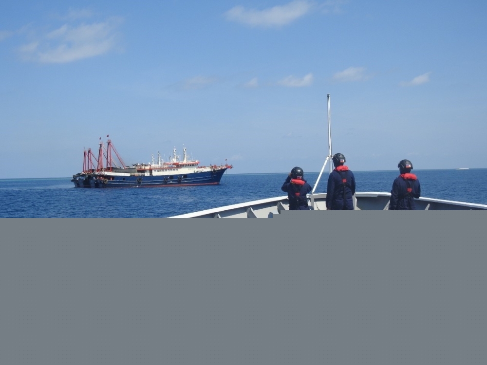 File photo: Philippine Coast Guard personnel survey several ships believed to be Chinese militia vessels in Sabina Shoal in the South China Sea, in a handout photo distributed by the Philippine Coast Guard on May 5 and taken according to source on April 2