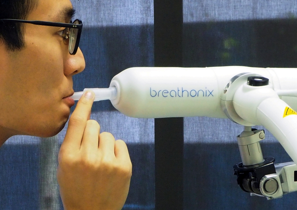 File photo: A staff member demonstrates the usage of Breathonix breathalyzer test kit developed by Breathonix, a start-up by the National University of Singapore, able to detect the coronavirus disease (COVID-19) within a minute according to the company, 