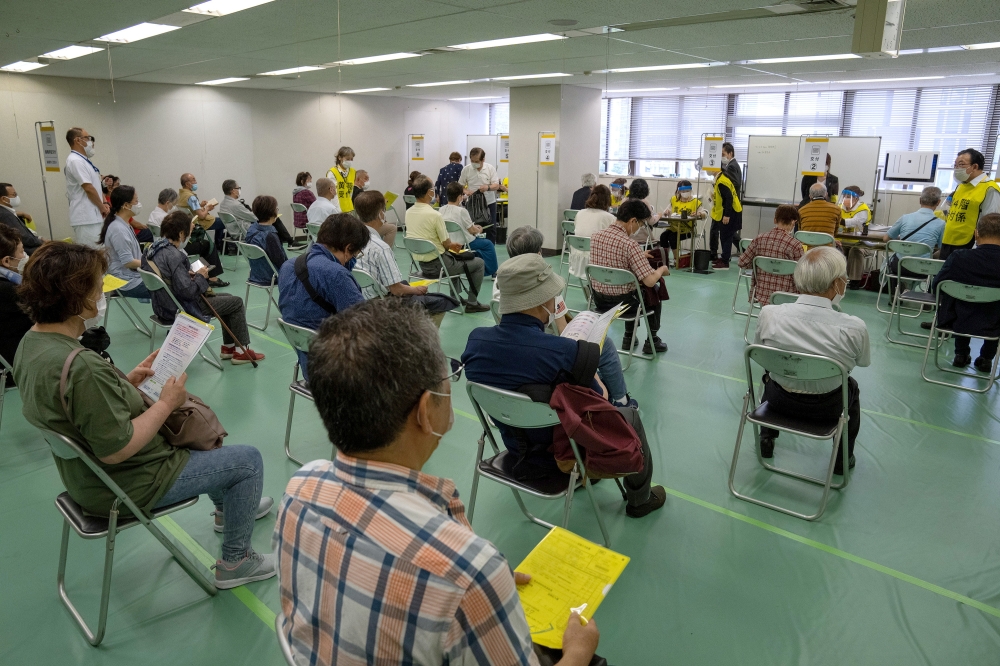People wait to be processed after arriving to receive the Moderna coronavirus disease (COVID-19) vaccine at the newly-opened mass vaccination centre in Tokyo, Japan, May 24, 2021. Carl Court/Pool via Reuters