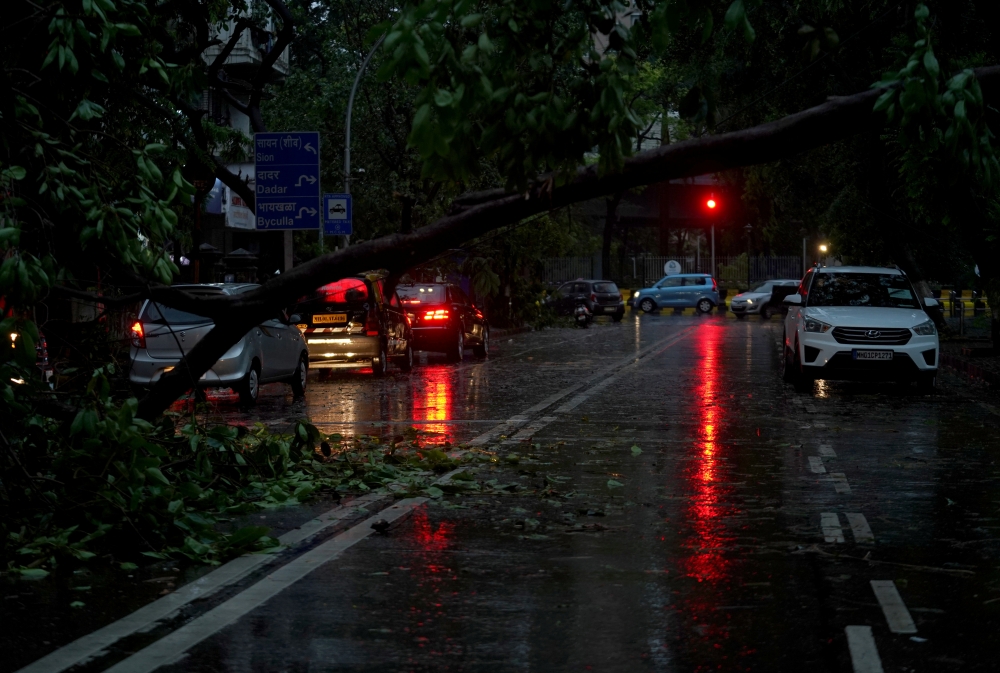Vehicles move past a fallen tree on a road after heavy winds caused by Cyclone Tauktae, in Mumbai, India, May 17, 2021. Reuters/Hemanshi Kamani