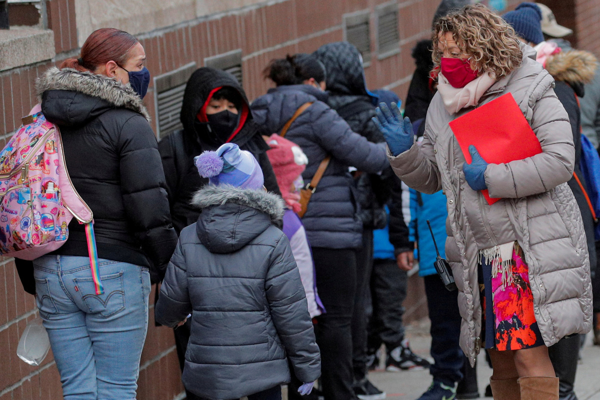 A principal greets students as they return to New York City's public schools for in-person learning, as the global outbreak of the coronavirus disease (COVID-19) continues, at P.S. 506 in Brooklyn, New York, U.S., December 7, 2020. REUTERS/Brendan McDermi