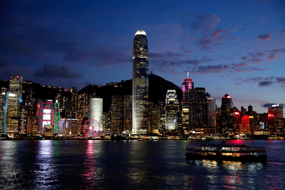 A boat crosses Victoria Harbour in front of a skyline of buildings during sunset. Hong Kong. Reuters/Tyrone Siu/File Photo